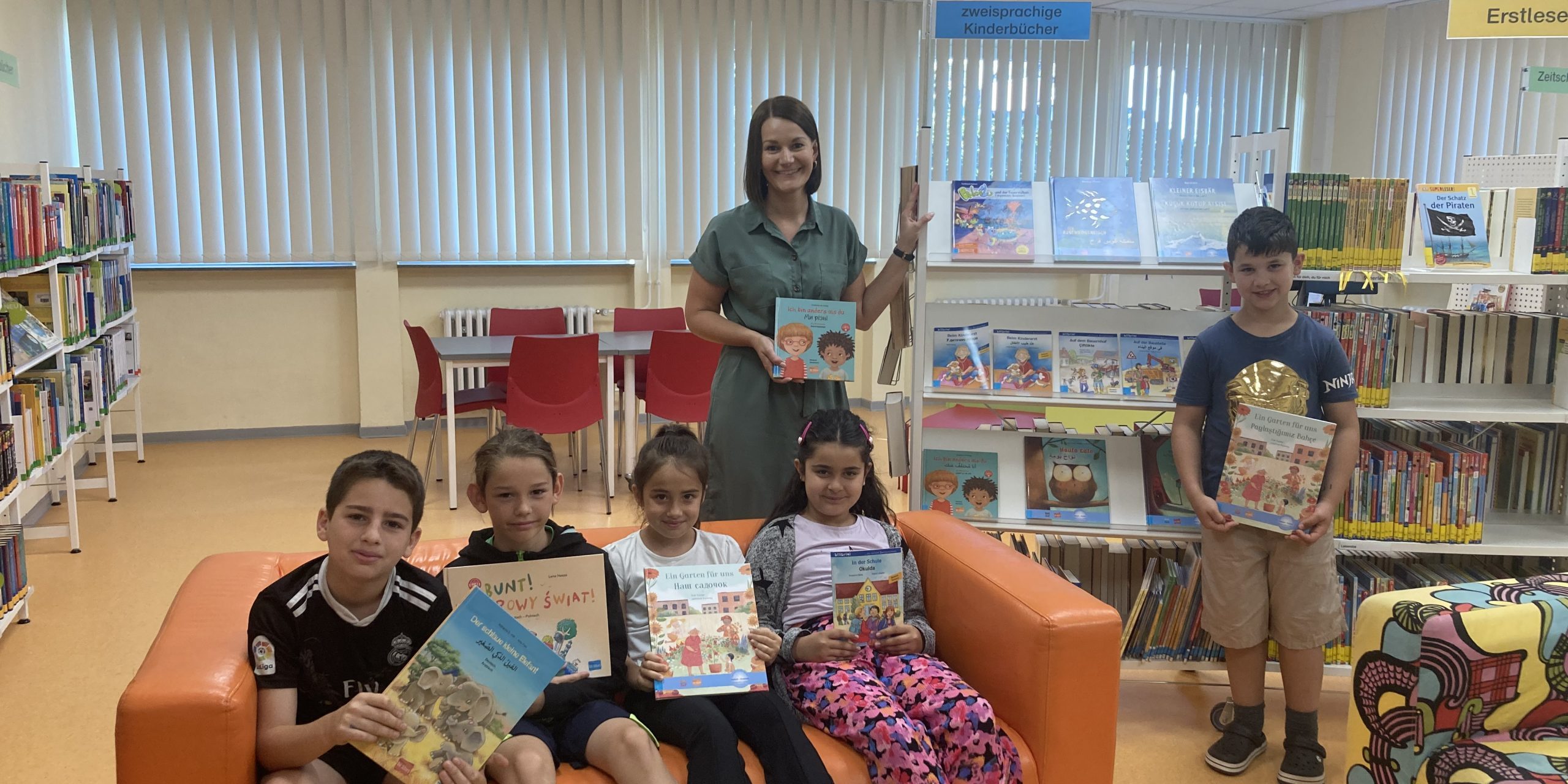 Mohammed Zain Al Najjar aus Syrien, Piotr Szymkowiak mit polnischen Wurzeln, Uliana Harshyana aus der Ukraine sowie die türkischstämmigen Zwillinge Sidelya und Ali Yalcin freuen sich gemeinsam mit Lehrerin Fabienne Bachmann über die neuen zweisprachigen Kinderbücher.
