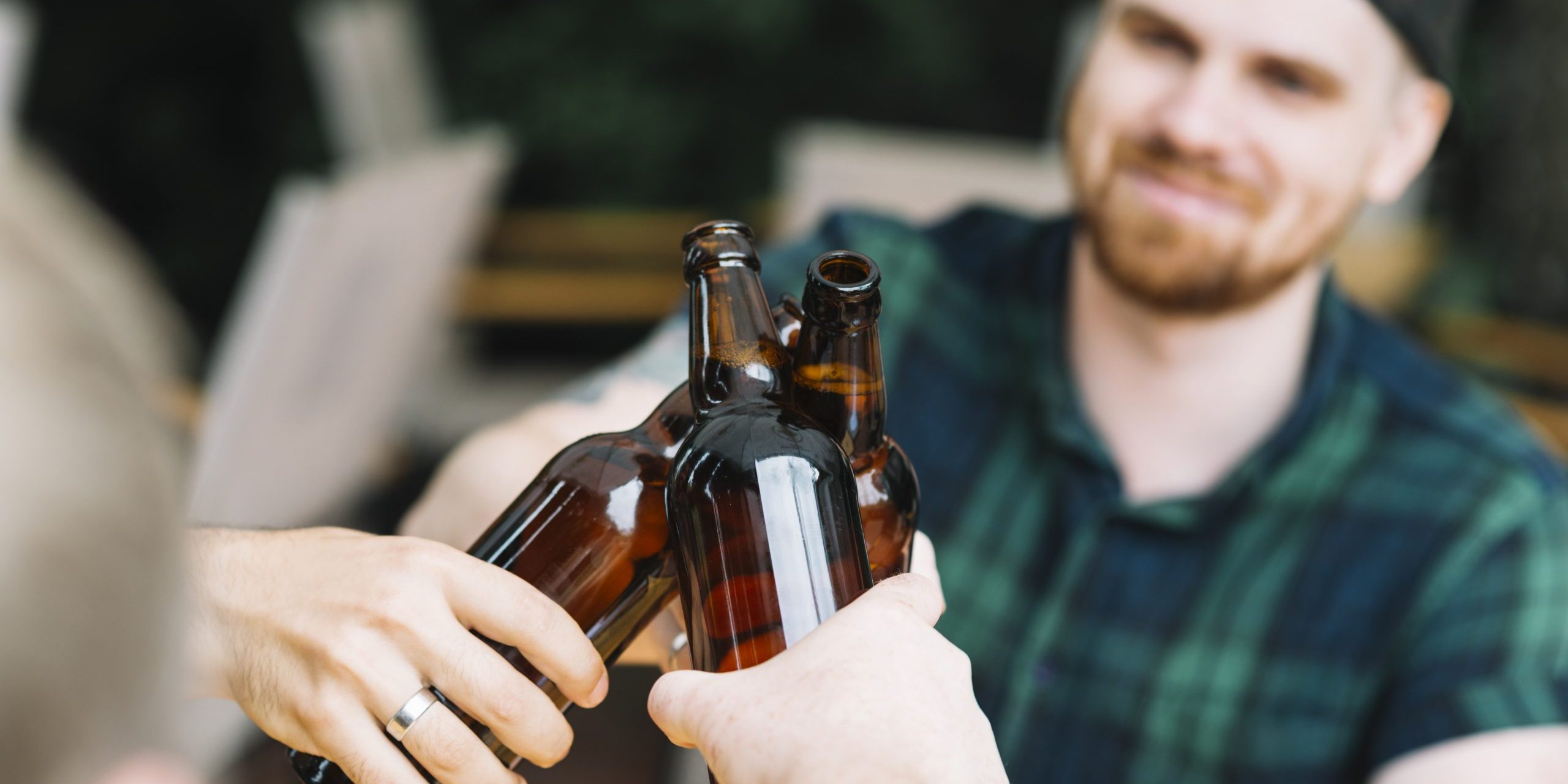 mann-der-die-glasflaschen-bier-mit-freunden-klirrt